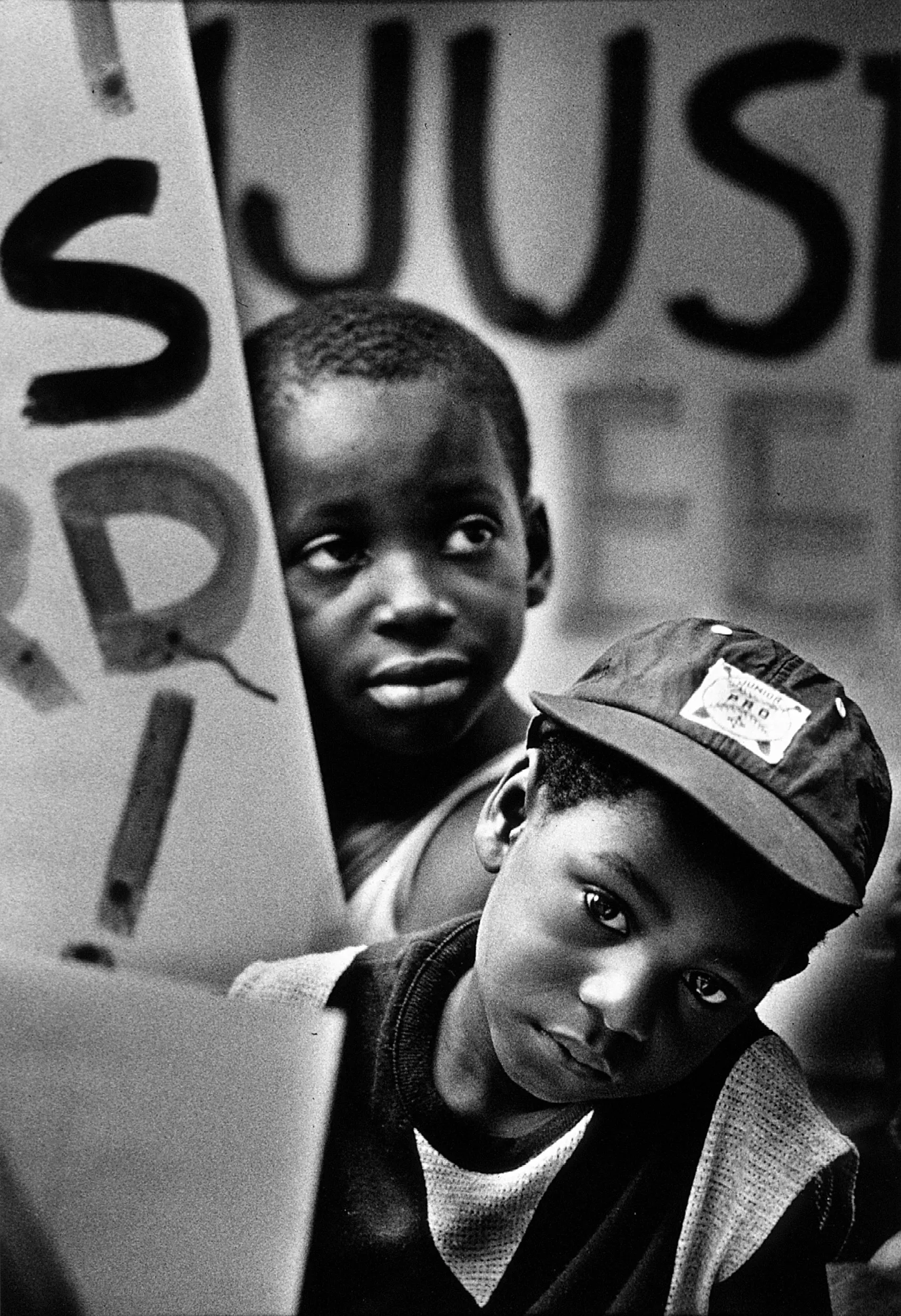 Hope — Kendall Bailey, 6, lower right, and Derrick Christoff, 7, listen to a preacher offer a prayer with a message directed at ending racism in America during a July 4th civil rights rally and march in Baton Rouge, Louisiana  (Photo by Stephan Savoia)  Published by The Baton Rouge Louisiana State-Times & Morning Advocate Circa Mid-Late 1980s