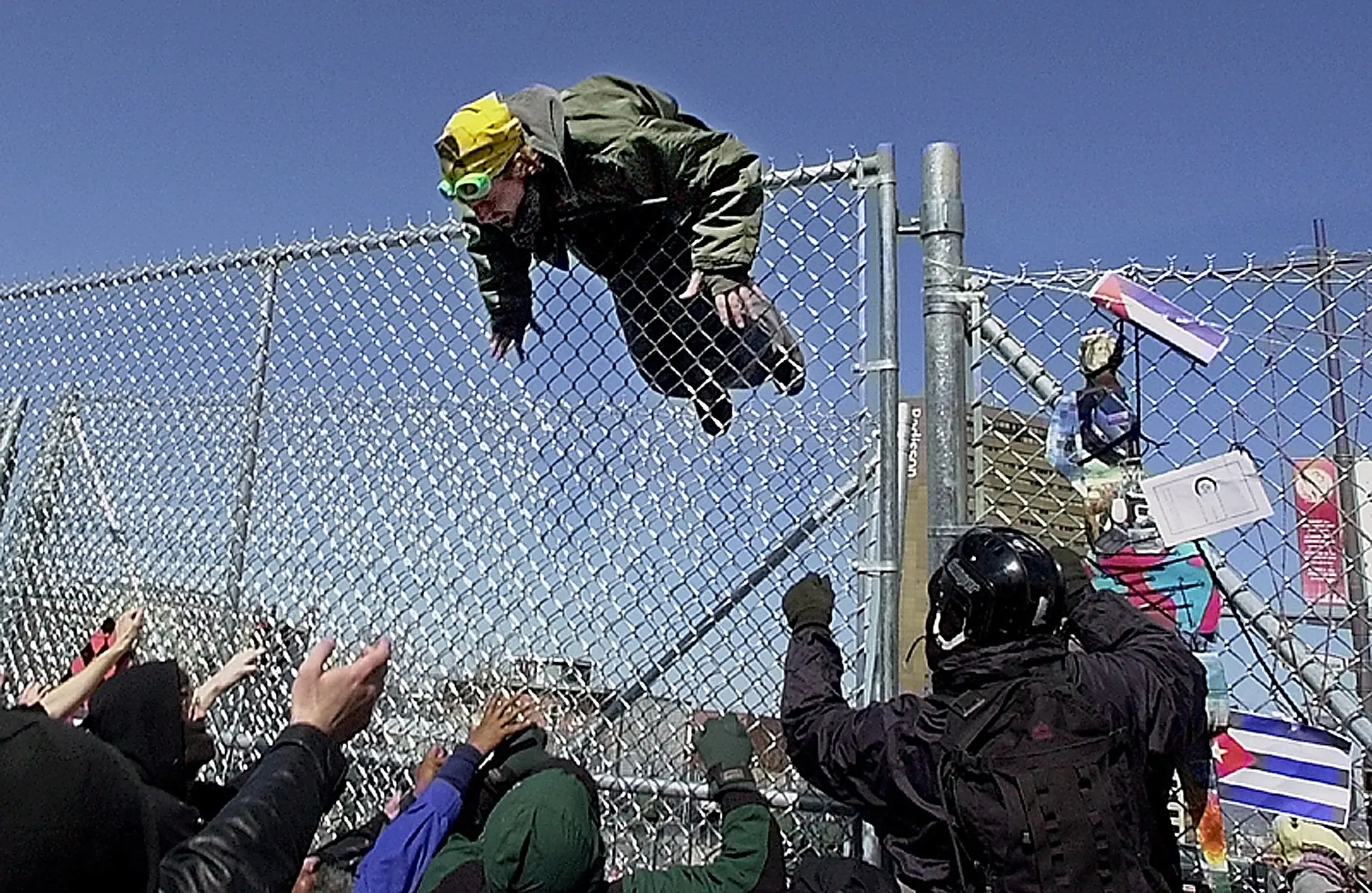 Stuck — A protestor hangs stuck atop a security fence as he and fellow protestors breach security surrounding the Summit of the Americas in Quebec City, Canada, Friday afternoon, April 20, 2001. Confrontations between police and protestors ensued after the fence came down as the Summit, where 34 heads of state from the western hemisphere gathered to discuss trade issues, got underway.  (AP Photo/Stephan Savoia)  © The Associated Press
