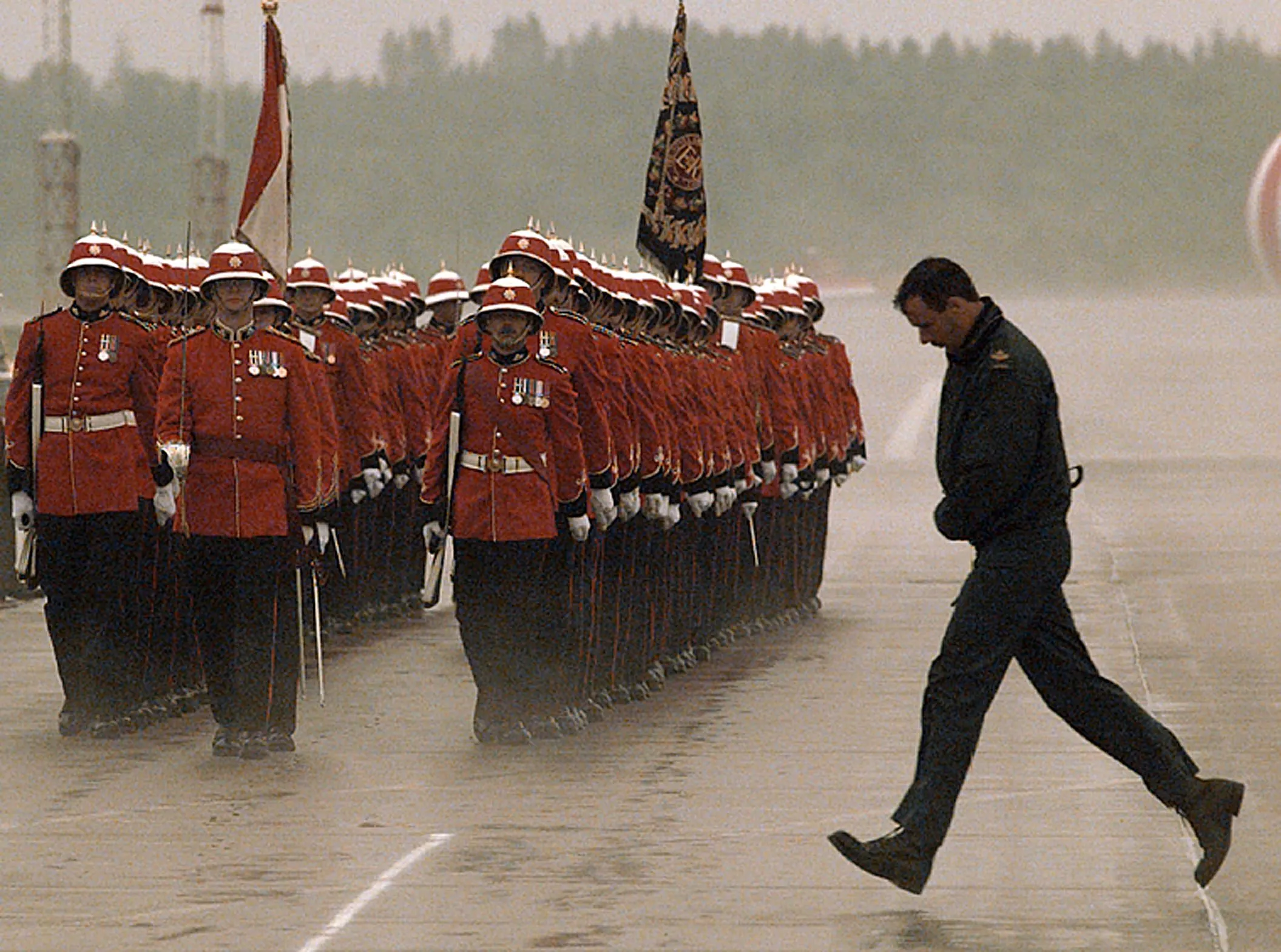 Pomp And Politics — Canadian Forces Master Corporal Kevin Colby runs across the tarmac reception area at the Canadian Air Base Shearwater during a light rain as the 2nd Battalion of the Royal Canadian Regiment marches out to greet Japan’s Prime Minister Tomiici Murayama upon his arrival in Dartmouth, Nova Scotia Canada Wednesday June 14, 1995. Murayama is in Canada to attend the G7 Summit which begins Thursday June 15, 1995.  (AP Photo/Stephan Savoia)  © The Associated Press