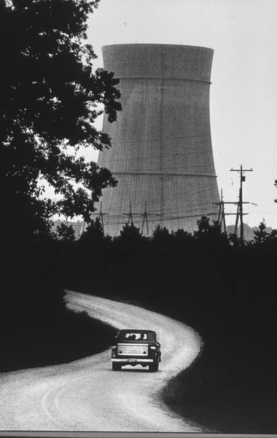 Where The Past Meets The Future — An early 1960's pickup truck drives a winding rural road adjacent to the Grand Gulf Nuclear Station's natural draft cooling tower in Claiborne County near Port Gibson, Mississippi. Construction of the nuclear power plant is nearing completion and is expected to be commissioned in 1985. Grand Gulf's reactor is the most powerful United States reactor and the 7th most powerful in the world.  (Photo by Stephan Savoia)  Published by The Monroe News-Star-World Circa 1983