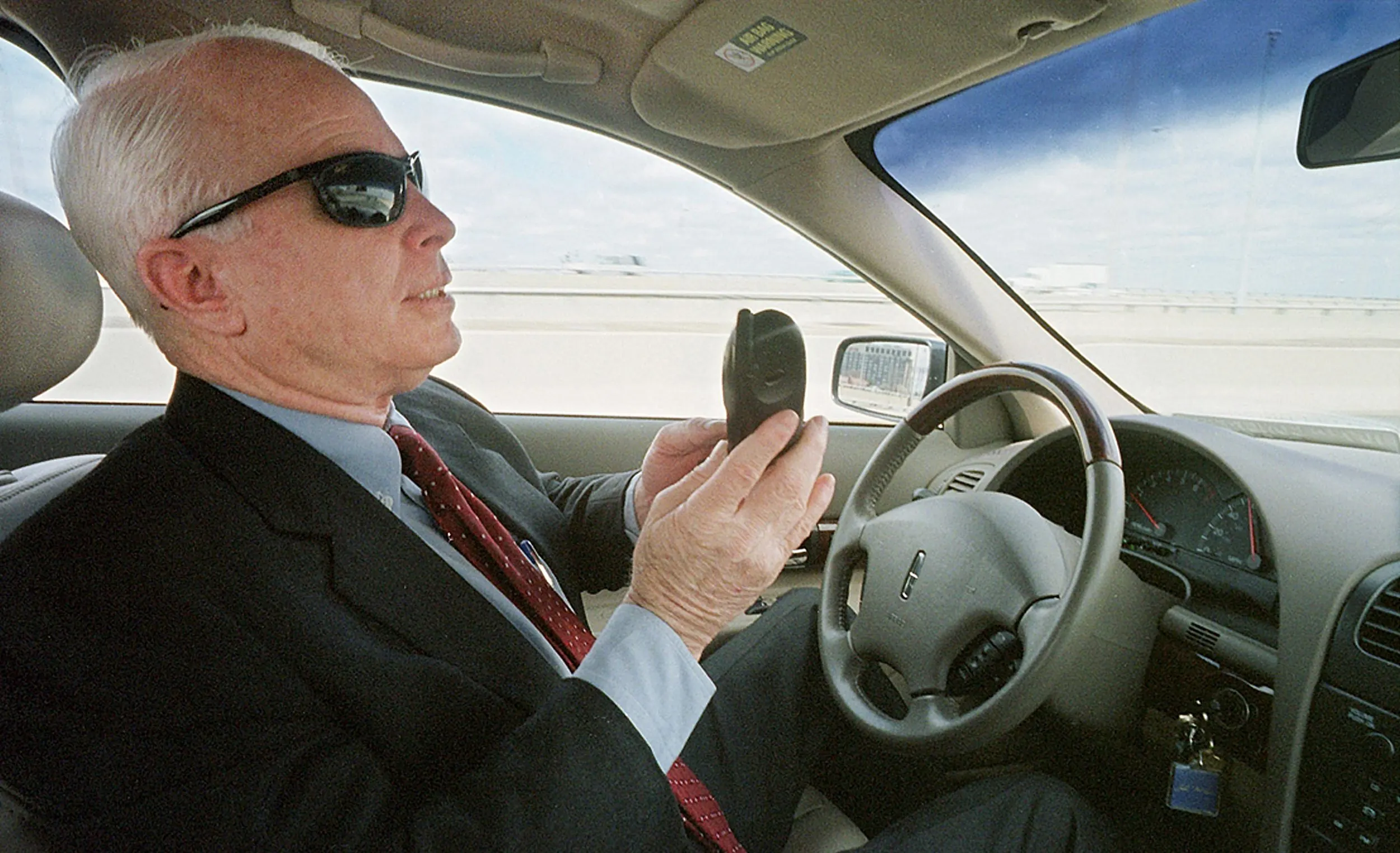 No Hands! — Arizona Republican Senator John McCain works his cell phone while driving on Interstate 395 in Arlington, Virginia, checking with staff members on the status of amendments to his campaign finance reform bill. McCain is returning to the Hill after delivering an address to the students of his former high school on Thursday afternoon, March 22, 2001.  (AP Photo/Stephan Savoia)  © The Associated Press