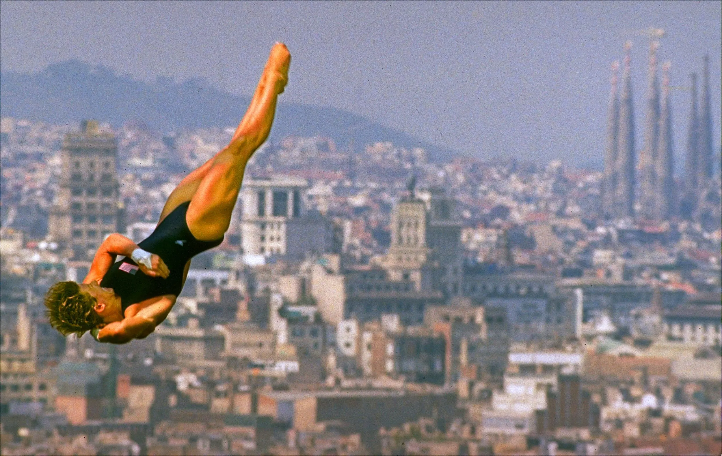 Athletics, Culture & Art — Mary Ellen Clark of Ft. Lauderdale, Florida, spins in mid-air during the 10 meter platform diving competition Sunday, July 26, 1992 at the XXV Olympiad in Barcelona, Spain. Clark placed second overall at the event's heat. Antoni Gaudí's Basílica i Temple Expiatori de la Sagrada Família, a UNESCO World Heritage Site, is seen in background at right.  (AP Photo/Stephan Savoia)  © The Associated Press