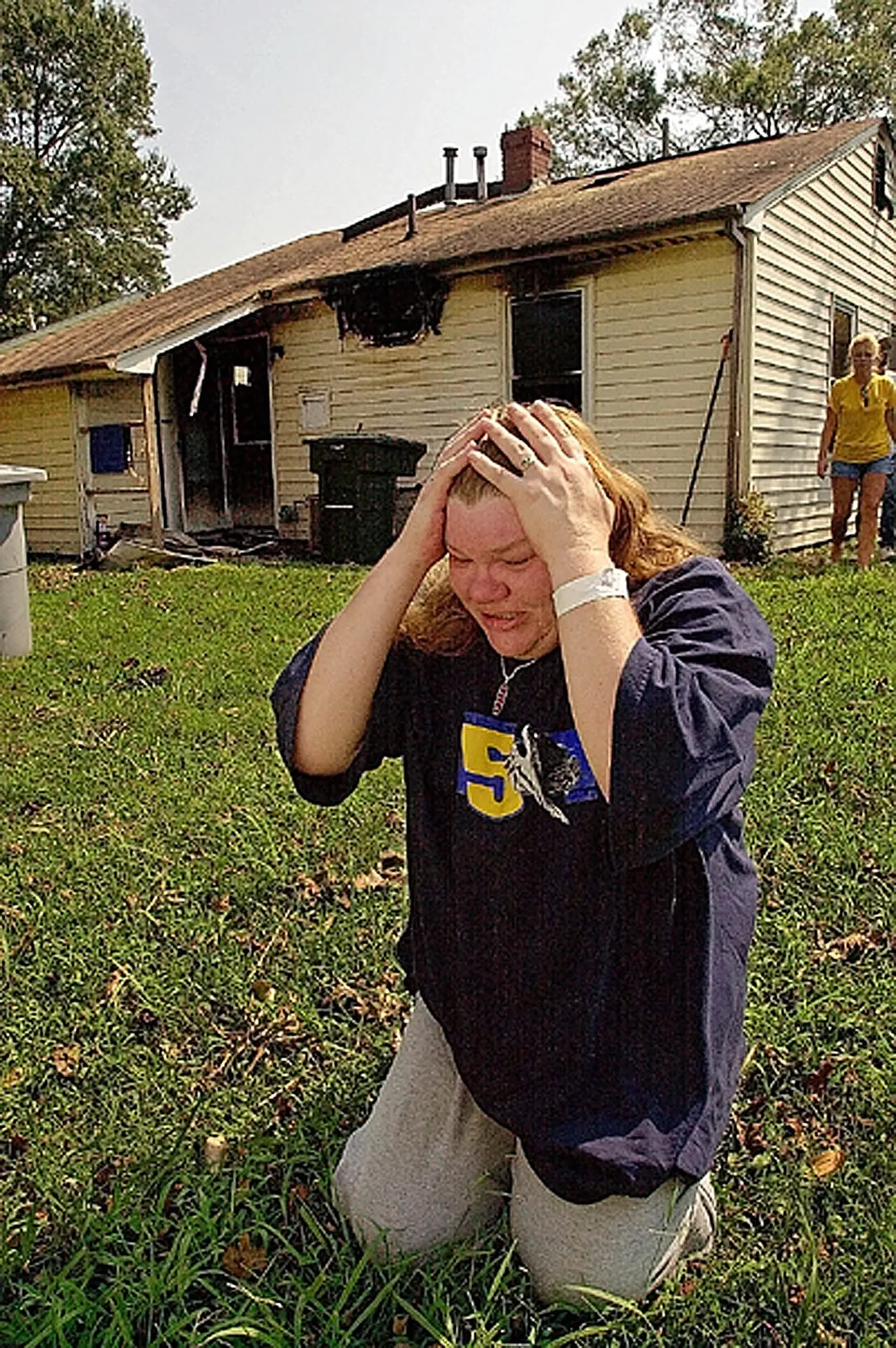Burned Out — Linda Butler kneels and brushes back her hair in an attempt to calm herself in the backyard of her Phelps Circle home in Hampton, Virginia, on Sunday afternoon, September 21, 2003. Butler's house was destroyed in a fire early Sunday morning when a candle she was using for light caught her bathroom on fire. Butler, like hundreds of thousands of Virginians, have been without electricity since Hurricane Isabel ripped through the area on Thursday.  (AP Photo/Stephan Savoia)  © The Associated Press