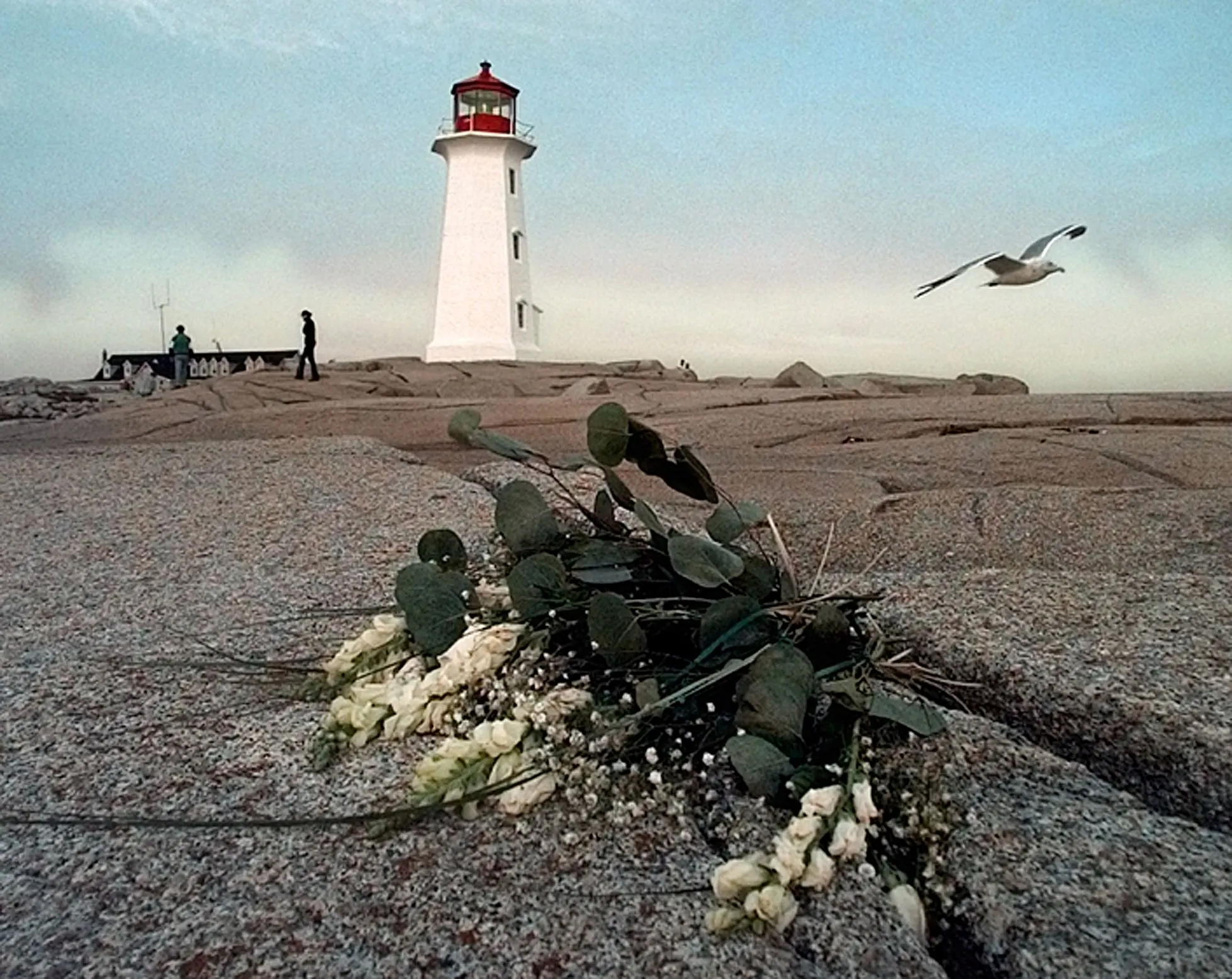 On A Seagull's Wings — Flowers, left in remembrance for victims of the Swissair Flight 111 crash, lie on the rocks of Peggy's Cove, in the Canadian Province of Nova Scotia, Canada as the sun begins to set on Wednesday evening, September 9, 1998. The Swissair MD-11 jetliner crashed into the Atlantic Ocean several miles off the coast of Peggy's Cove killing all 229 on board Wednesday, September 2, 1998.  (AP Photo/Stephan Savoia)  © The Associated Press