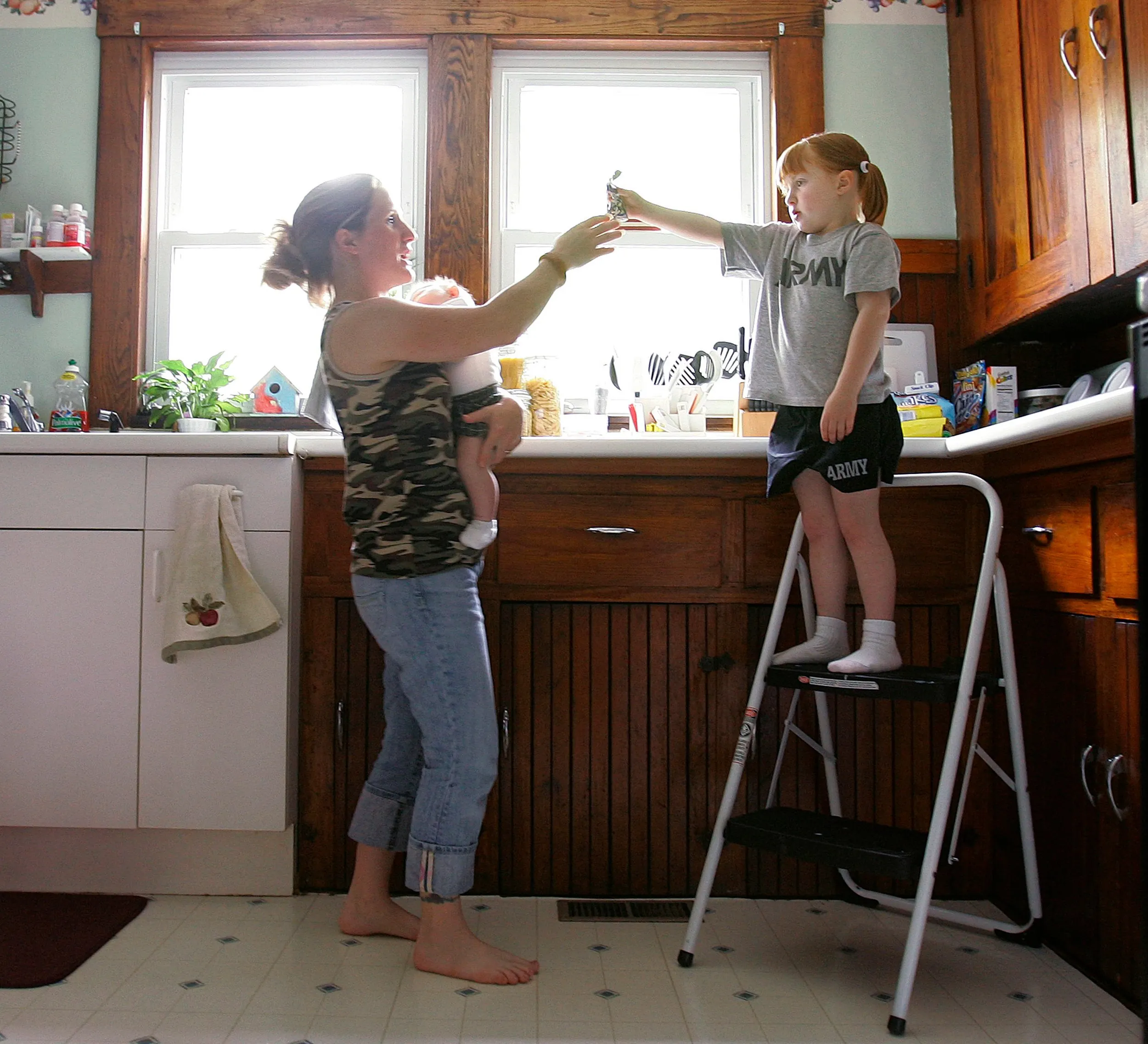 Missing Clint… To Life (2 of 2) — Melissa Story holds her son baby Clint Jr. while handing her daughter Dela a juice pouch while standing in the kitchen of their Palmer, Massachusetts, apartment Wednesday, May 16, 2007.  (AP Photo/Stephan Savoia)  © The Associated Press