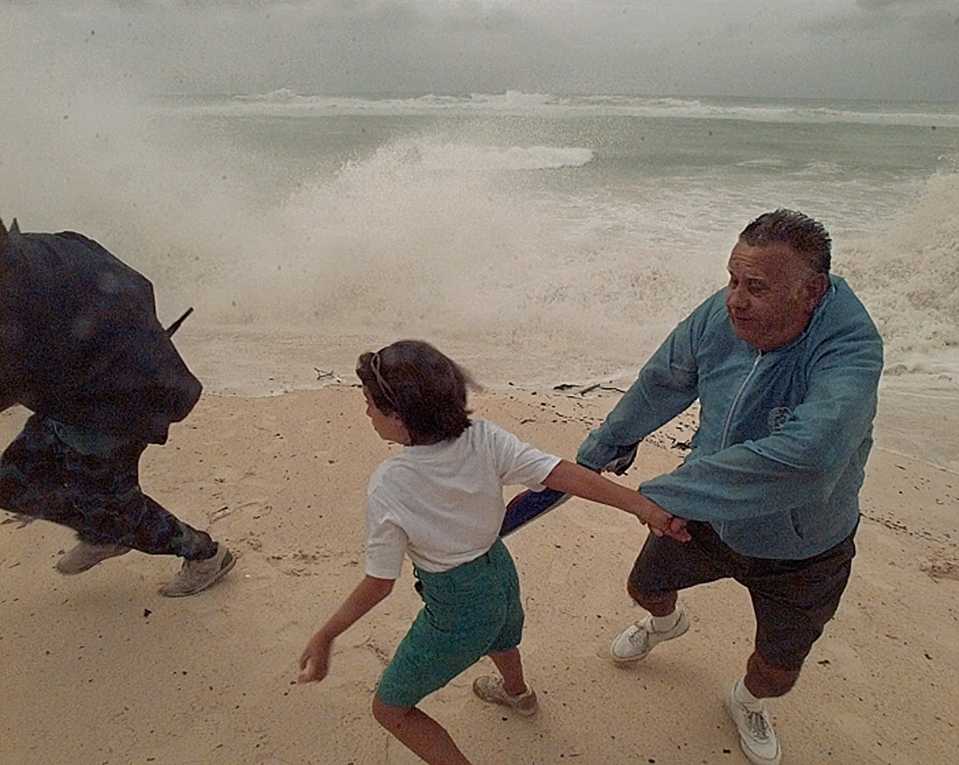 Retreat — M.F. Perry, right and his granddaughter Kimberly Tatum, 8, are among a group of storm watchers who turn and run from the rising surf and crashing waves on Elbow Beach Monday morning, August 14, 1995 as Hurricane Felix barrels down on the Island of Bermuda. Felix is expected to make landfall early Tuesday morning, August 14th on the North Atlantic Island.  (AP Photo/Stephan Savoia)  © The Associated Press